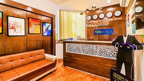 A hotel reception area with a wooden reception desk, a leather sofa, and a mannequin with boxing gloves. - Fabhotel Admiral (Mumbai)