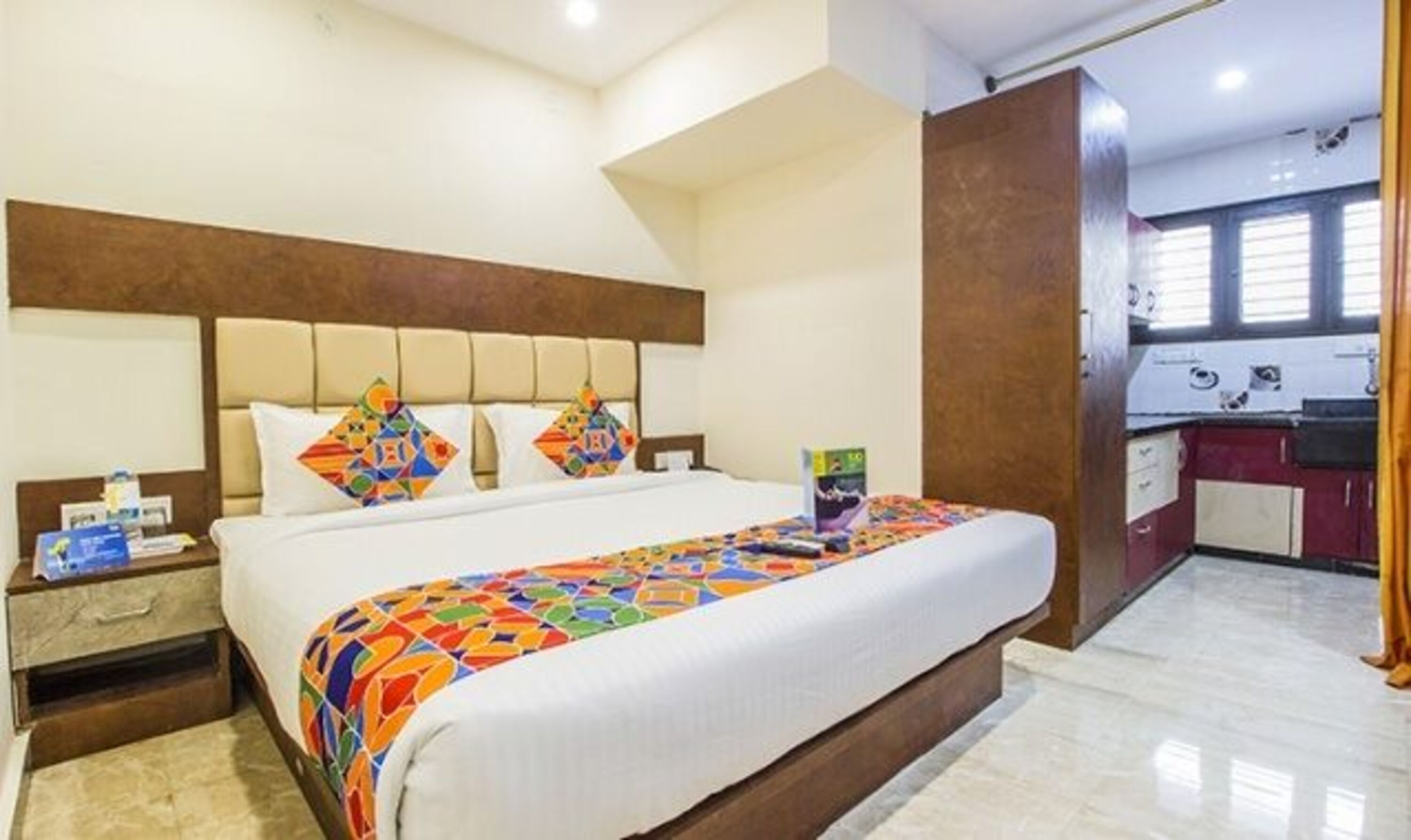 Una habitación de hotel con una cama grande, una mesita de noche, un escritorio y una kitchenette.