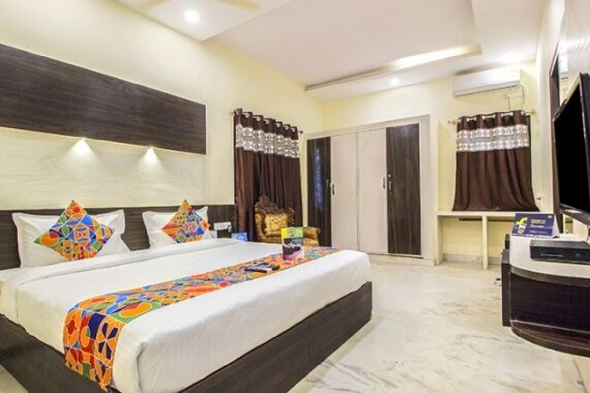 A hotel room with a large bed, a desk with a computer, a wardrobe, and a television.