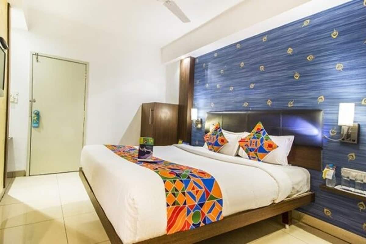 A hotel room with a bed, a nightstand, a wall-mounted TV, and a door.