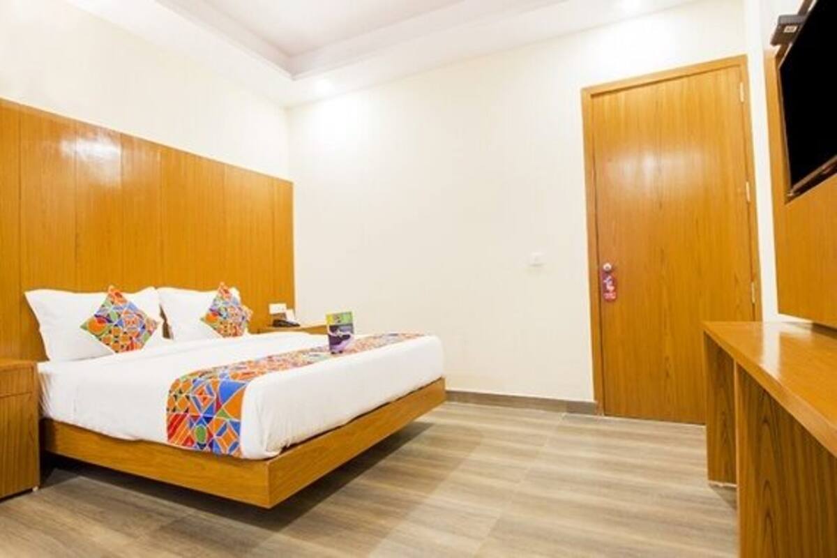 A hotel room with a wooden bed, a nightstand, a desk, and a wardrobe.