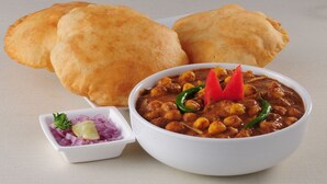 A bowl of curry with chickpeas and red chilies, accompanied by flatbread and a small bowl of sliced onions and herbs. - FabHotel Marol Metro (Mumbai)