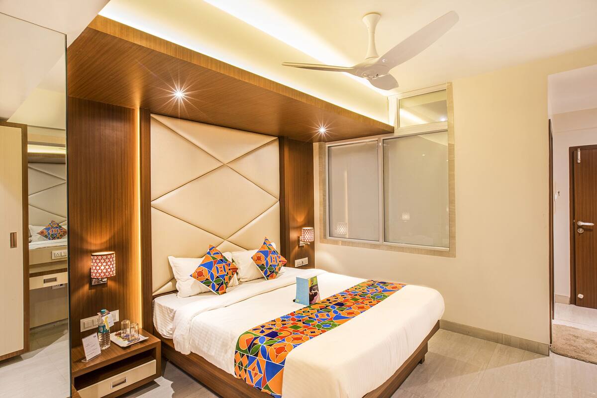 A modern hotel room with a large bed, a ceiling fan, and a nightstand with a lamp.