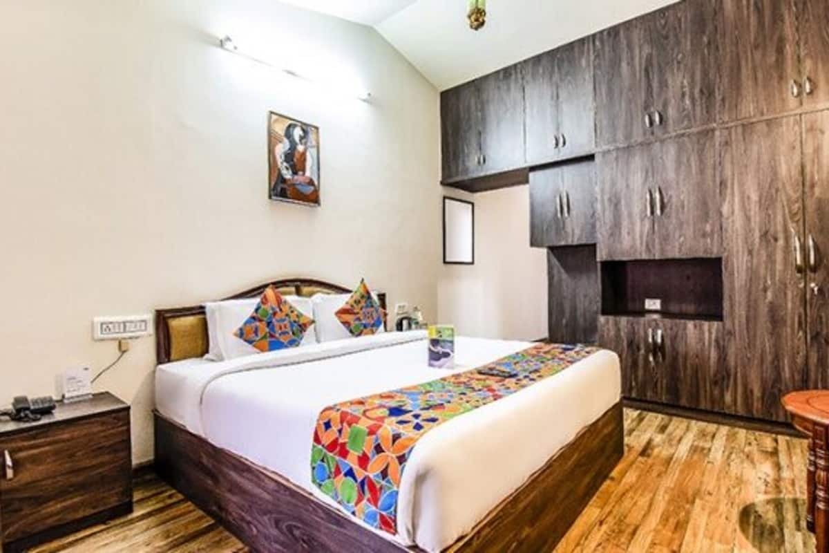 A bedroom with a large bed, wooden wardrobe, and a small table.