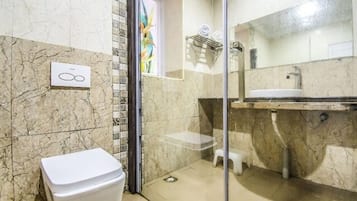 A bathroom with a toilet, a sink, and a shower area.