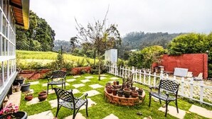 A patio with a checkered lawn, outdoor furniture, and potted plants. - Fabescape St. Clouds (Ootacamund)