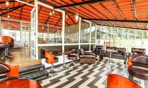 A spacious indoor area with a high ceiling, large windows, and a chevron-patterned floor.