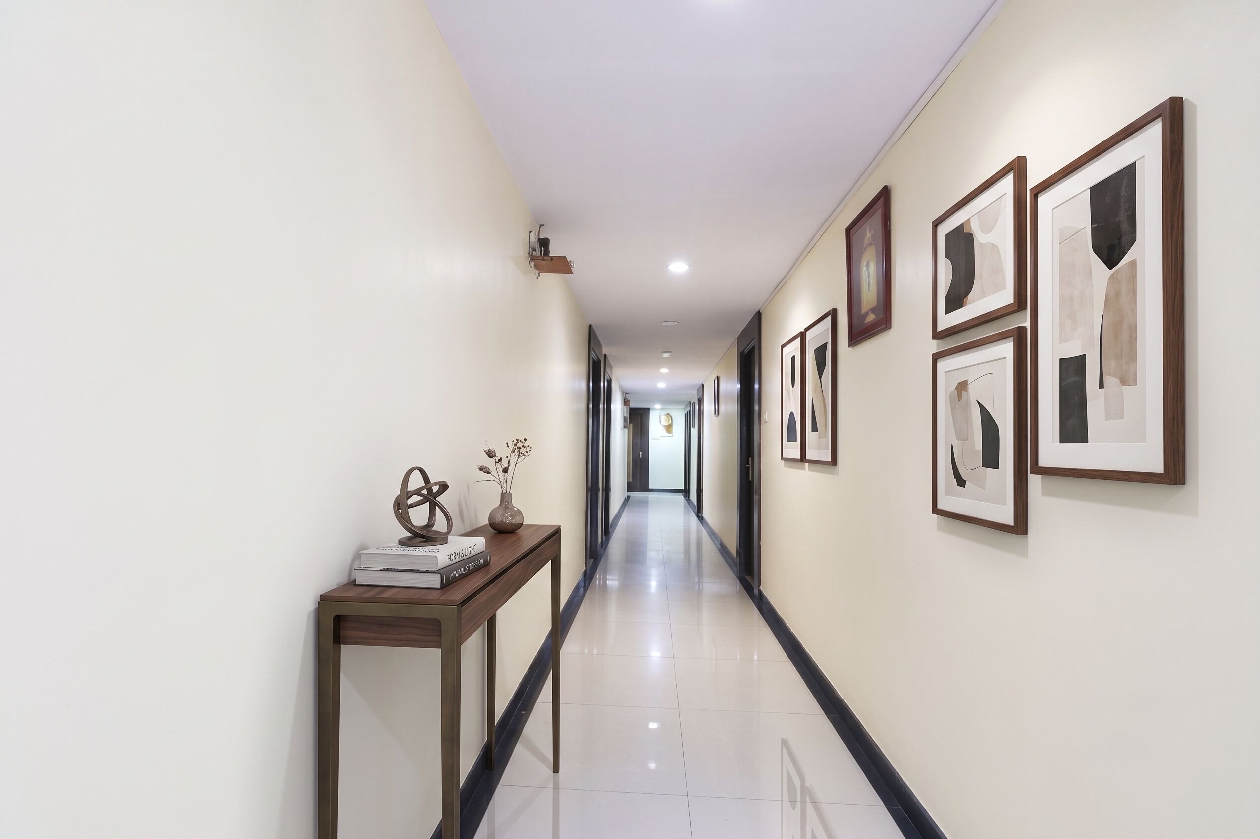 A hallway with a wooden console table, books, a vase with flowers, and framed artwork on the walls.