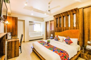 A hotel room with a large bed, a desk, and a TV. - Fabhotel Sahar Garden (Mumbai)