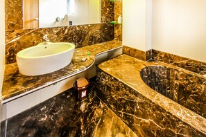 Un baño con lavamanos de mármol, bañera y tocador.