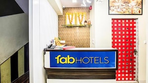 Un mostrador de recepción con un letrero que dice "fabHOTELS" y una pared con un estampado rojo detrás.