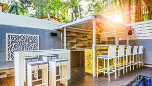 A covered outdoor seating area with white chairs and a pool table. - FabHotel Casa Kiara With Pool Side Bar, Calangute (Calangute)