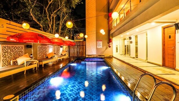 A pool area with a tiled floor, lounge chairs, and umbrellas. - FabHotel Casa Kiara With Pool Side Bar, Calangute (Calangute)