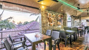 Un restaurante al aire libre con paredes de piedra, mesas y sillas.