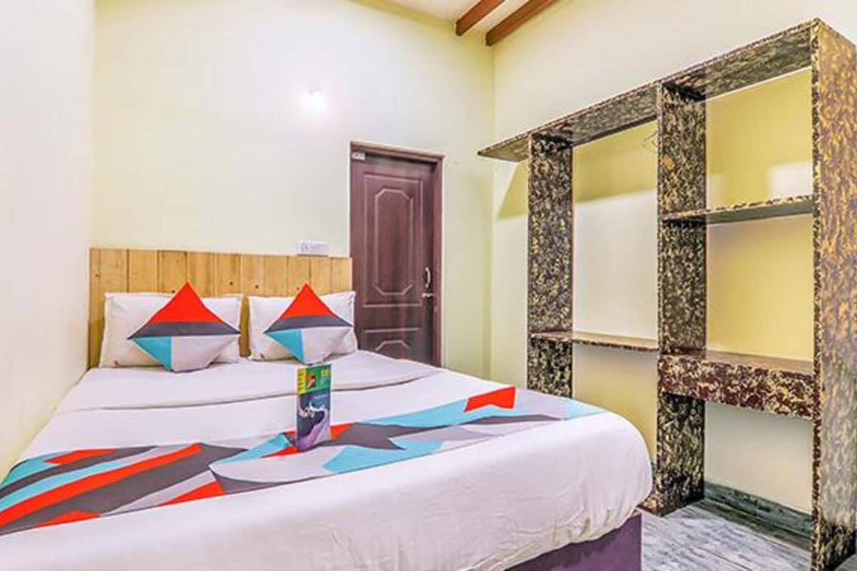 A bedroom with a bed, pillows, a door, and a wardrobe.