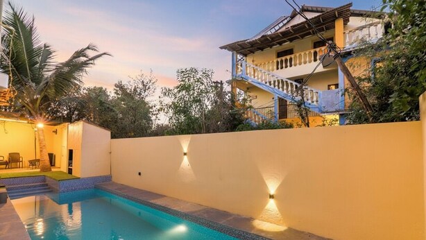 Una piscina con superficie de agua azul cristalina, rodeada por un muro blanco bajo.