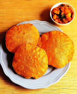 Three round, golden-brown fried items on a white plate, with a small bowl of mixed vegetables in the background. - FabExpress Victoria With Pool, Baga Beach (Baga)