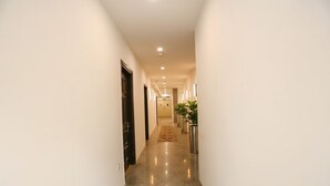 Un pasillo estrecho y bien iluminado con piso pulido, que conduce a una puerta al final.