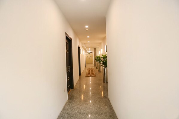 A well-lit, narrow hallway with a polished floor, leading to a door at the end. - FabExpress Victoria With Pool, Baga Beach (Baga)