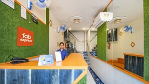 A hotel reception area with a reception desk, a sign for 'Tab Express', and a staircase leading to the upper floors. - FabHotel Orange Suites (Mumbai)