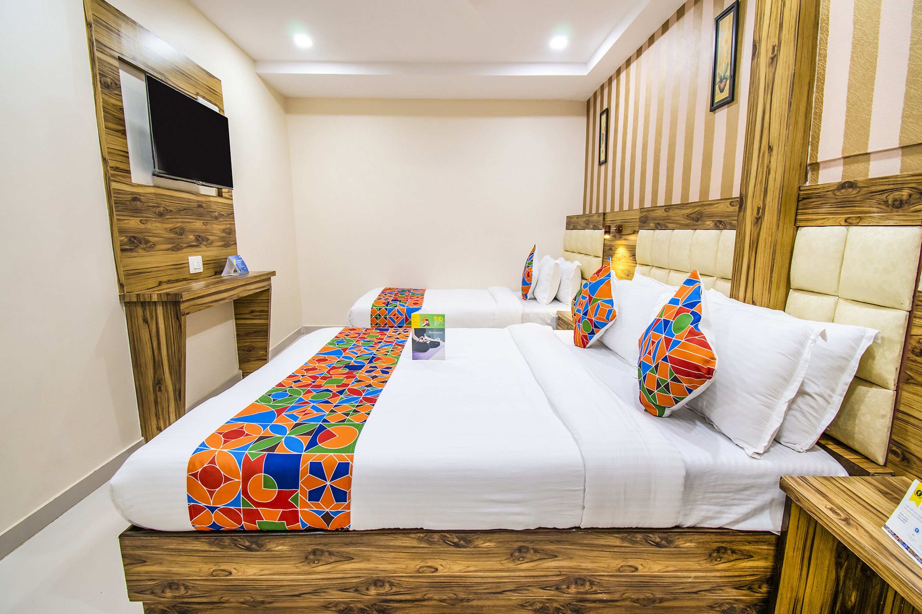 Une chambre d’hôtel avec un grand lit, un téléviseur fixé au mur et une tête de lit en bois.