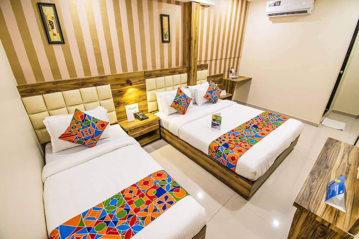 A hotel room with two beds, striped wallpaper, wooden headboards, and a small wooden table.