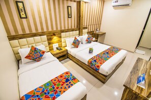 A hotel room with two beds, striped wallpaper, wooden headboards, and a small wooden table. - FabHotel Orange Suites (Mumbai)