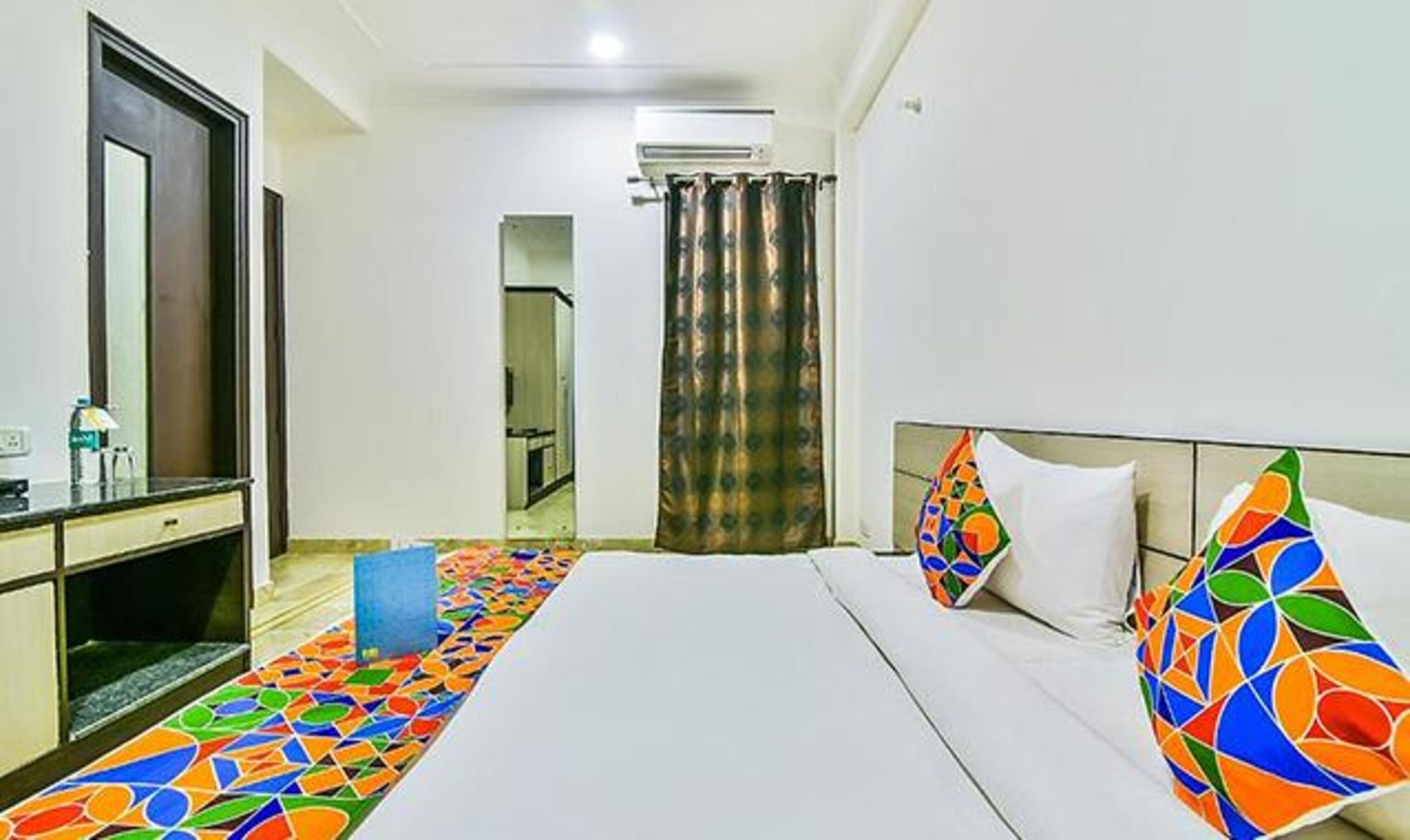 A hotel room with a bed, a desk, and a mirror.