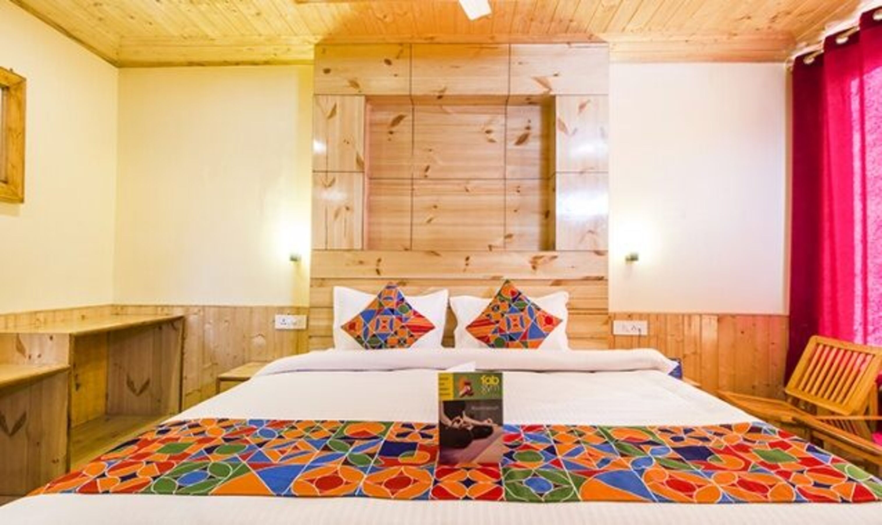 Une pièce aménagée comme un chalet en bois, avec un lit, un rideau rouge et un banc en bois.