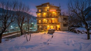 A multi-story hotel with a 'fabexpress' sign, surrounded by snow-covered landscape and bare trees. - FabHotel Shami Inn (Manali)