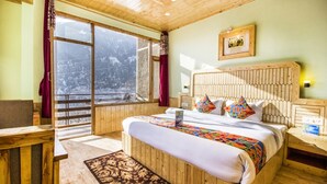 A bedroom with a large bed, wooden headboard, a window with a view of mountains, and a wooden floor. - FabHotel Shami Inn (Manali)