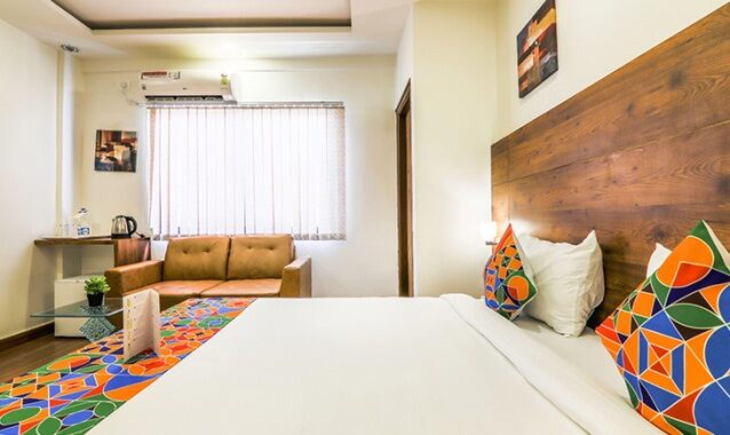 A hotel room with a bed, a sofa, a coffee table, and a window with curtains.