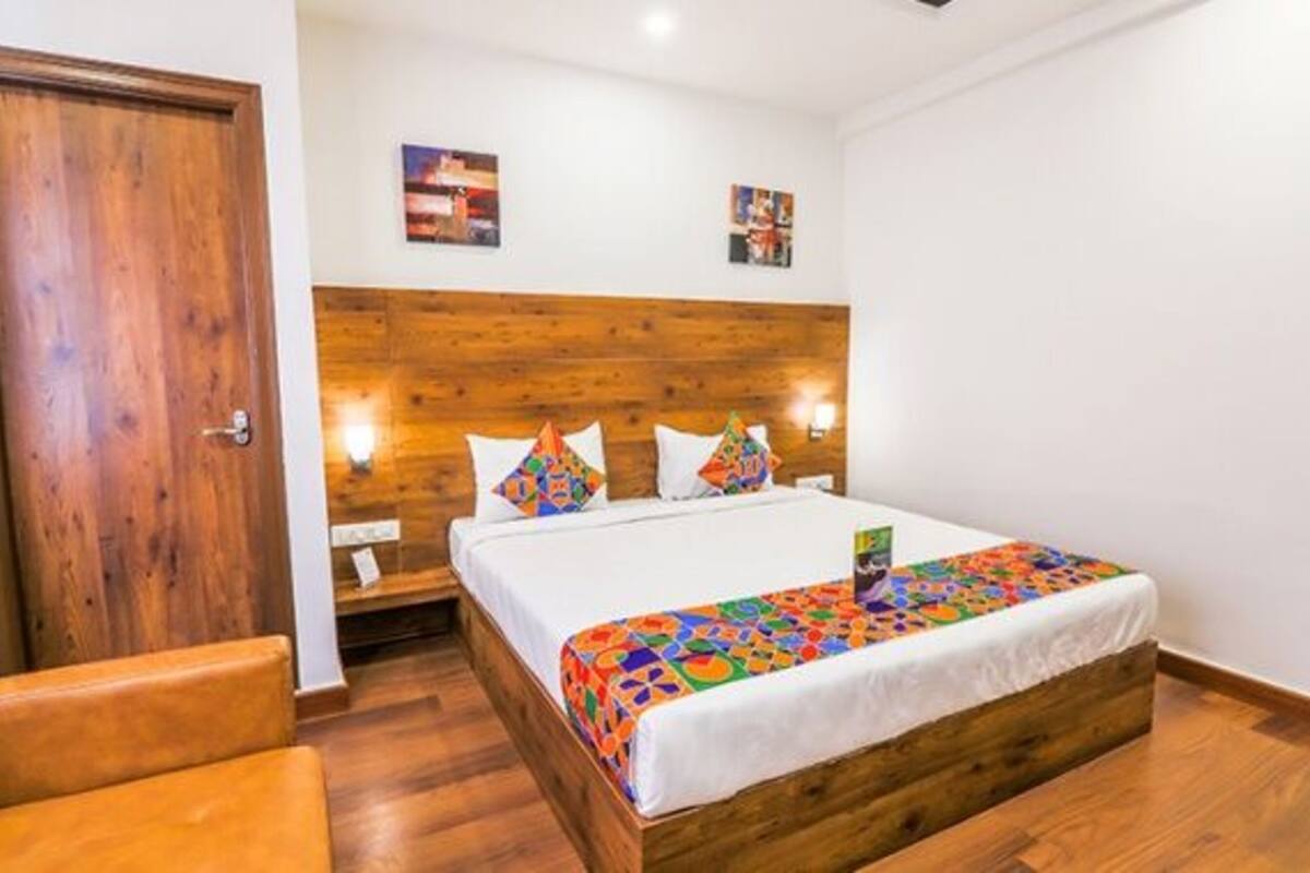 A room with a wooden headboard, a bed with colorful bedding, a nightstand, and a wooden door.