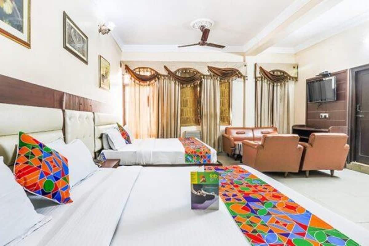 A hotel room with two beds, a sofa, a TV, and a desk.