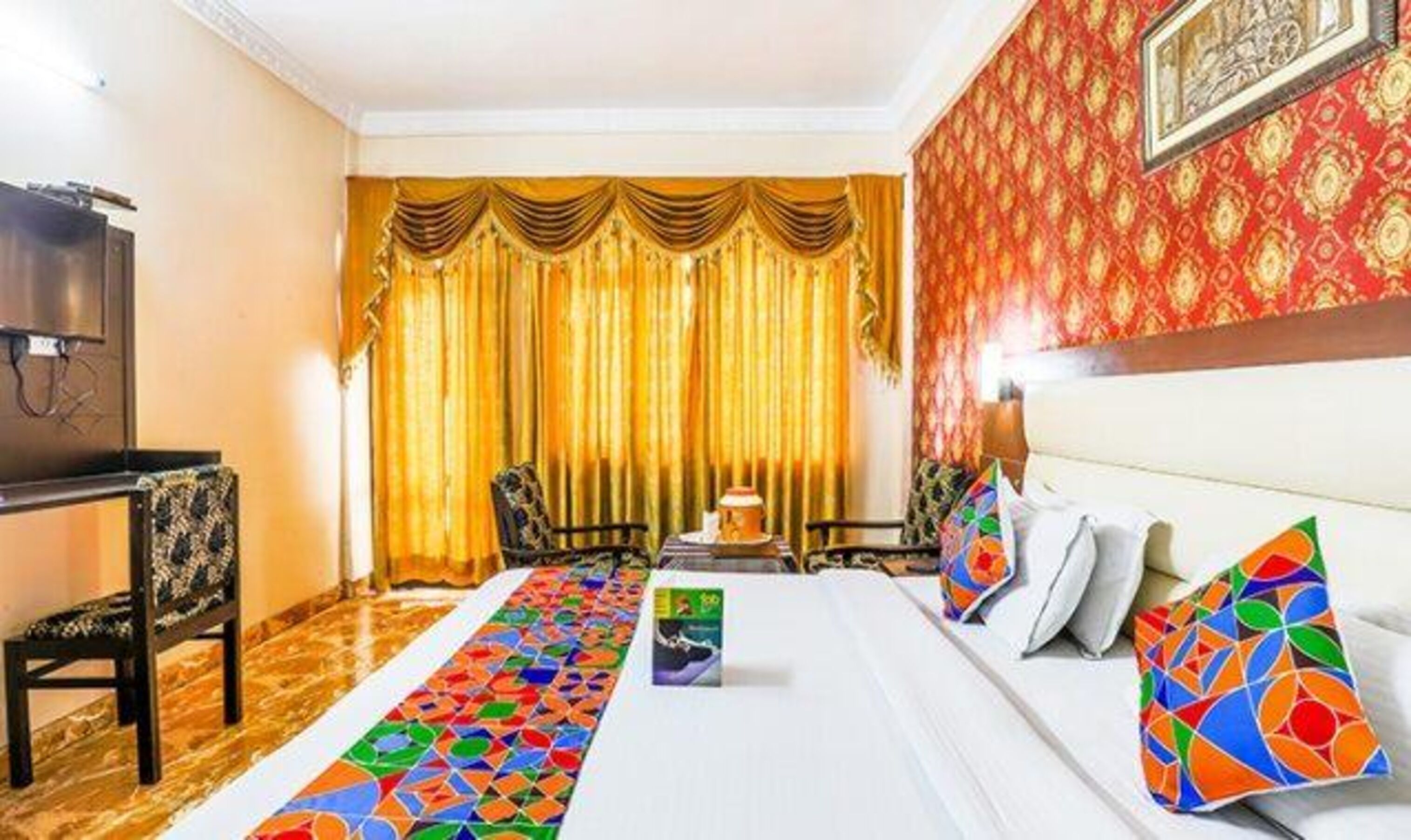 A hotel room with a bed, a TV, a desk, and a chair.