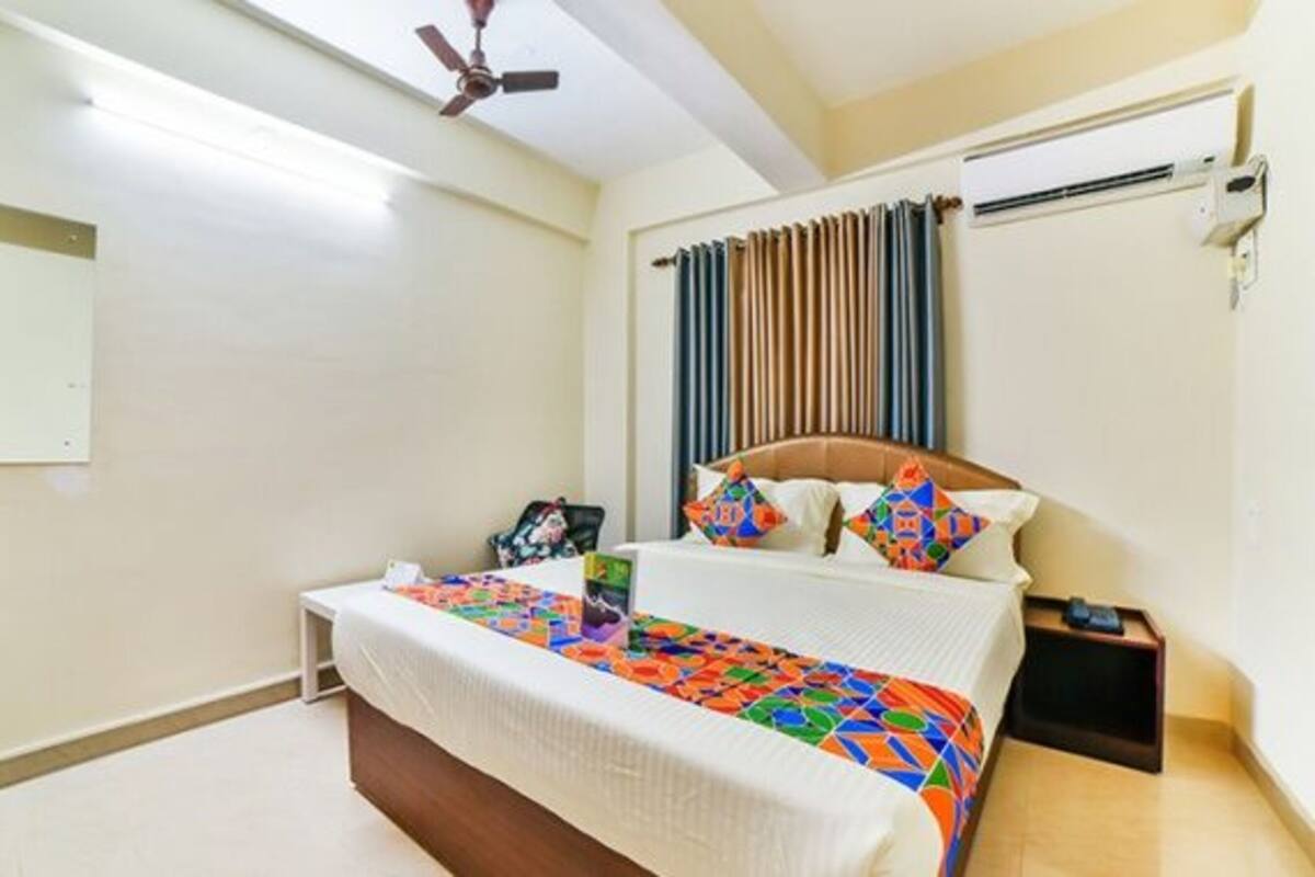 A bedroom with a bed, a bedside table, a ceiling fan, and a window with curtains.