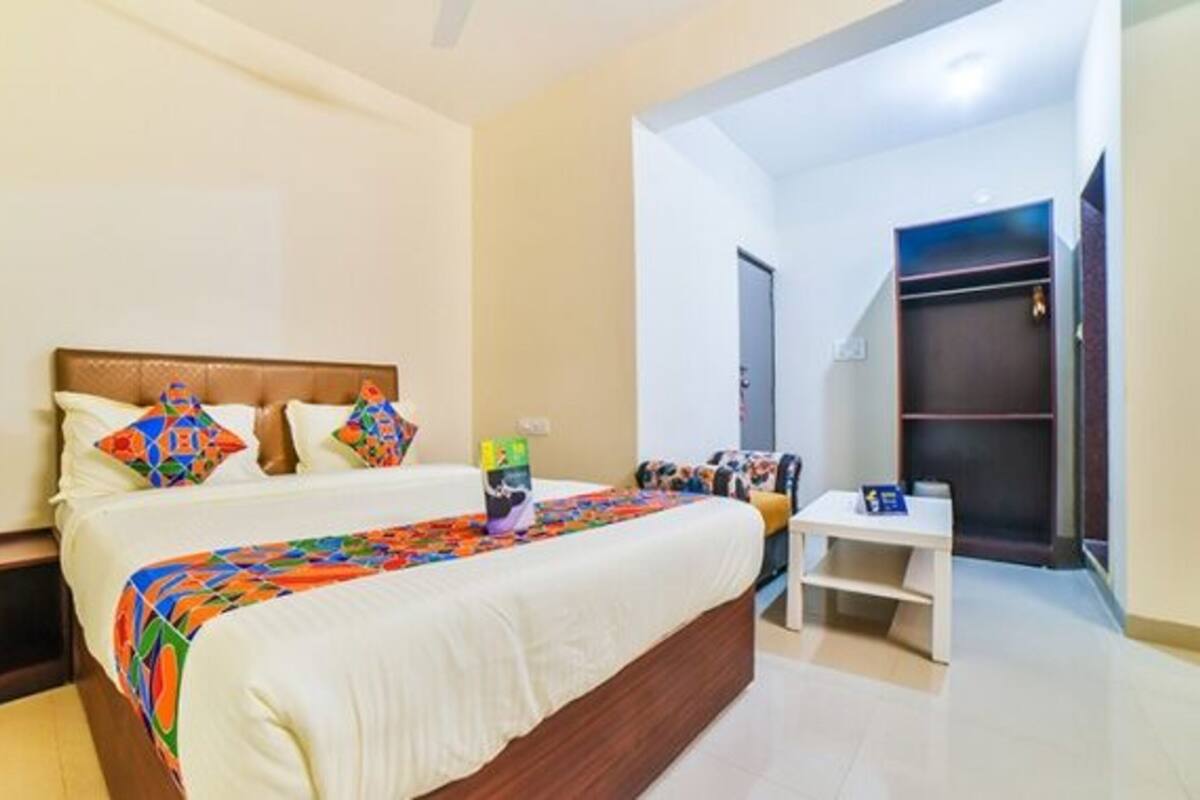 A bedroom with a bed, bedside tables, a wardrobe, and a small seating area.
