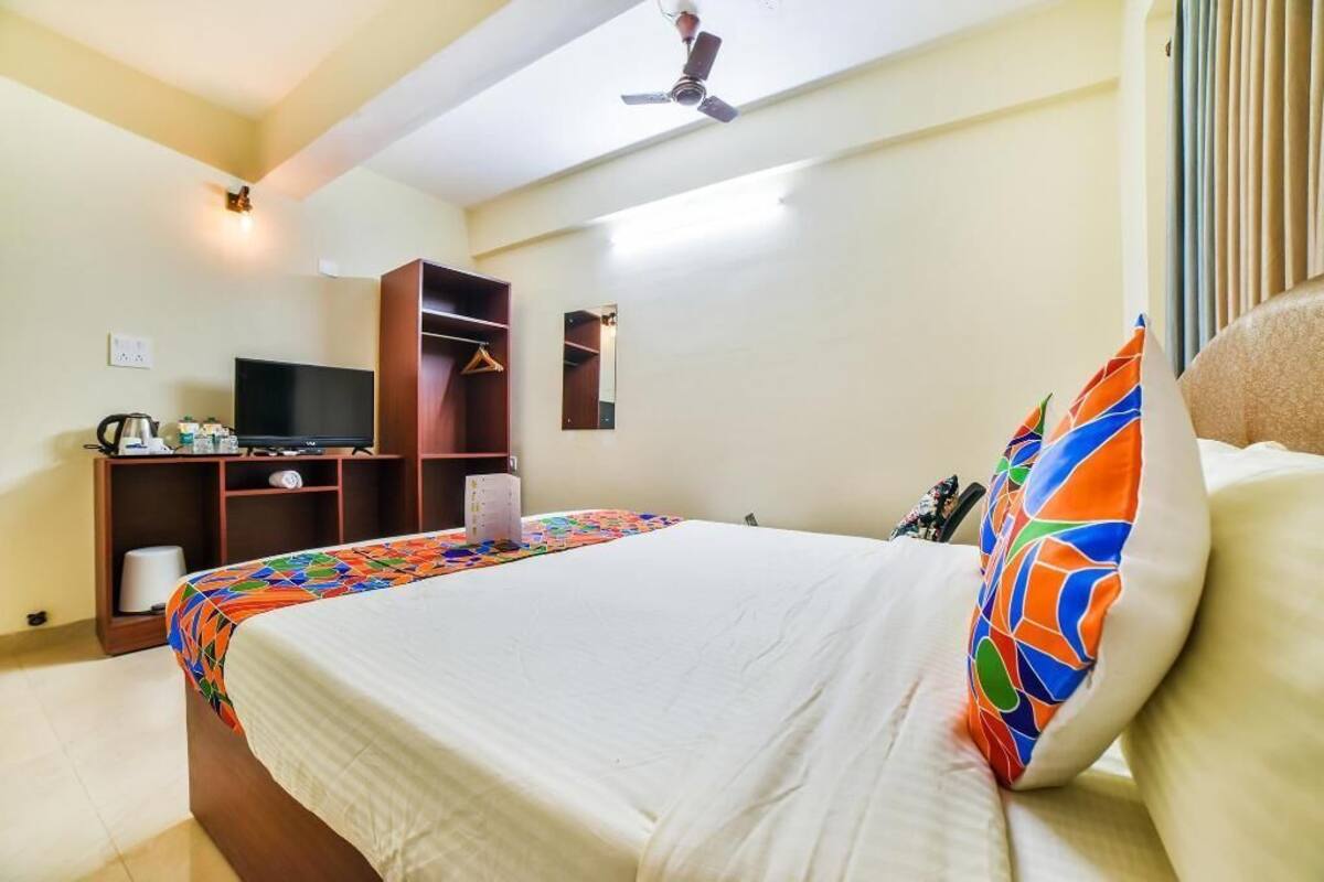 A hotel room with a bed, a TV, a wardrobe, and a ceiling fan.