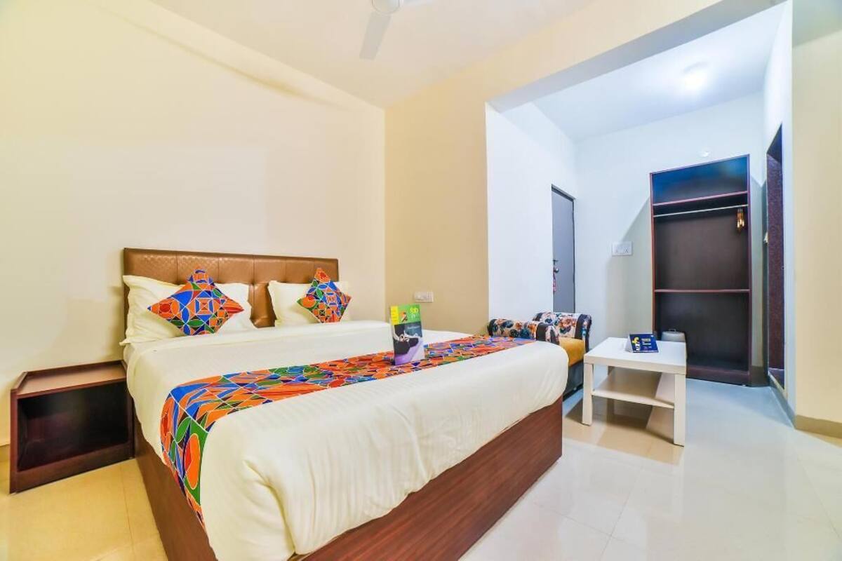 A hotel room with a bed, bedside table, and a wardrobe.