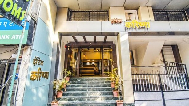 A hotel entrance with a staircase, potted plants, and a sign in a foreign language. - FabExpress Karishma - Shivaji Nagar, Pune (Pune)