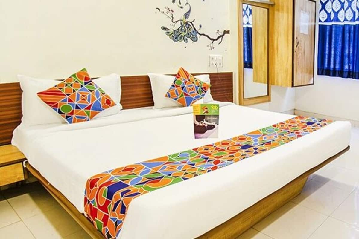 A hotel room with a large bed, a desk, a chair, and a window with blue curtains.
