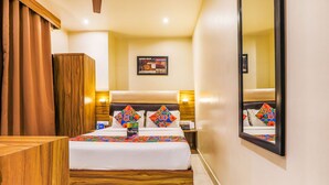 Habitación de hotel con cama, cabecera de madera, mesitas de noche, un espejo y un cuadro en la pared.