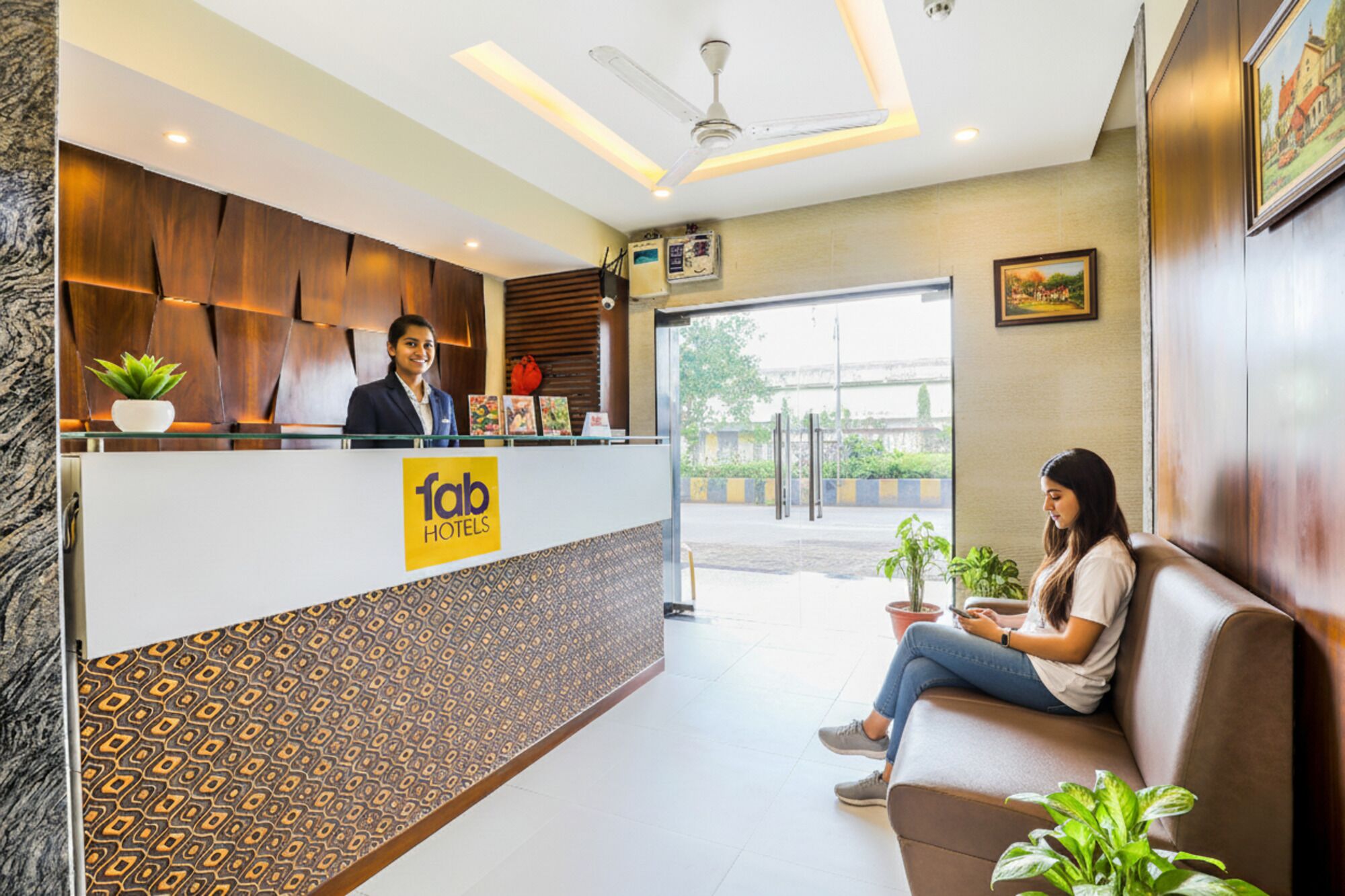 A hotel reception area with a modern design, including a reception desk, seating area, and a view of the outside.