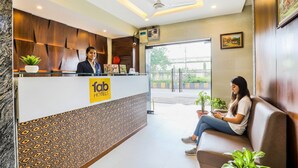 A hotel reception area with a modern design, including a reception desk, seating area, and a view of the outside. - Fabhotel Landmark Residency (Navi Mumbai)