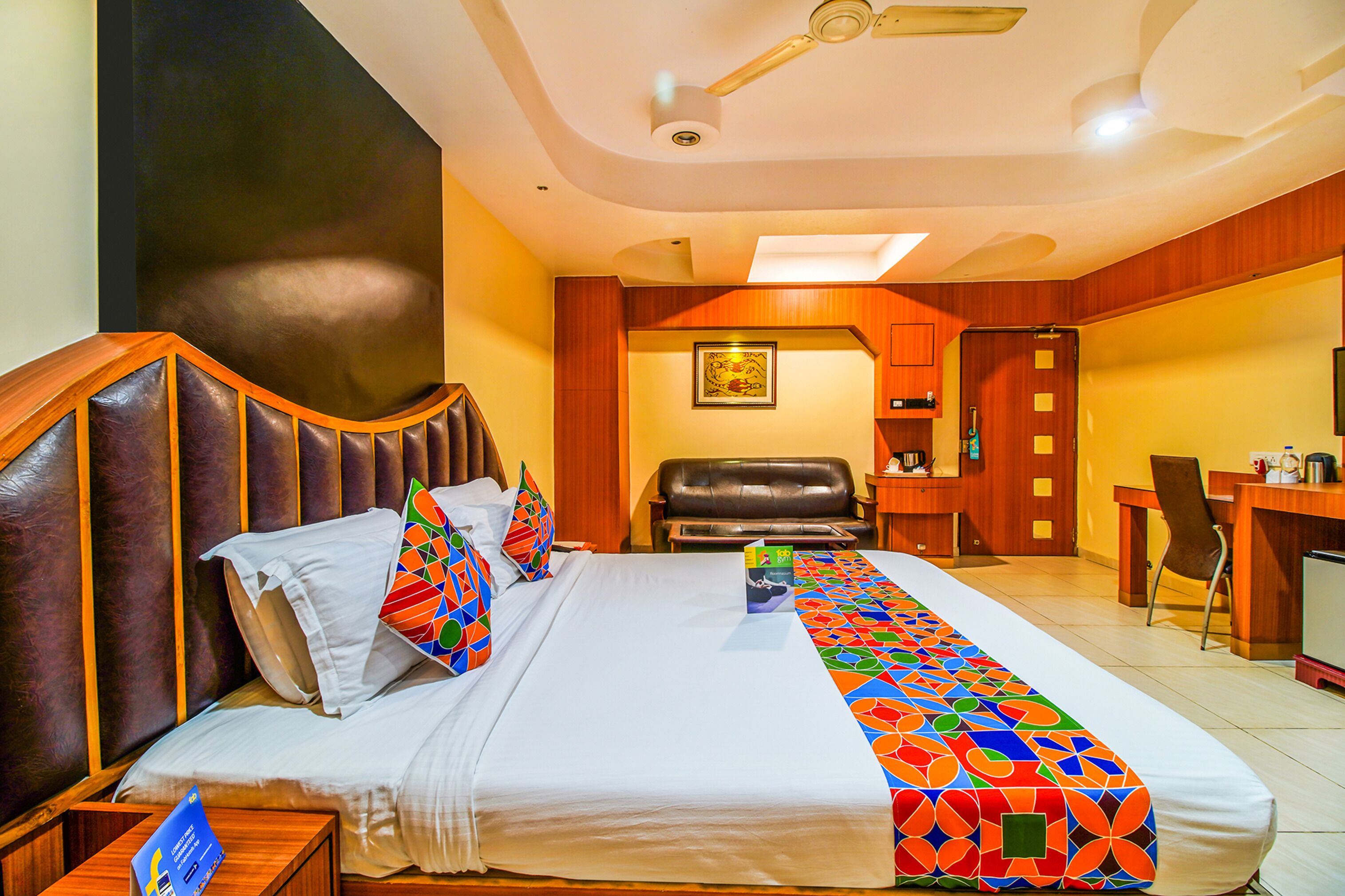 A hotel room with a large bed, a desk, a chair, and a dining area.