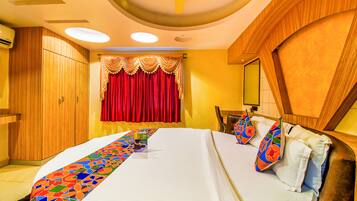 A hotel room with a large bed, a wooden wardrobe, a red curtain, and a ceiling fan.