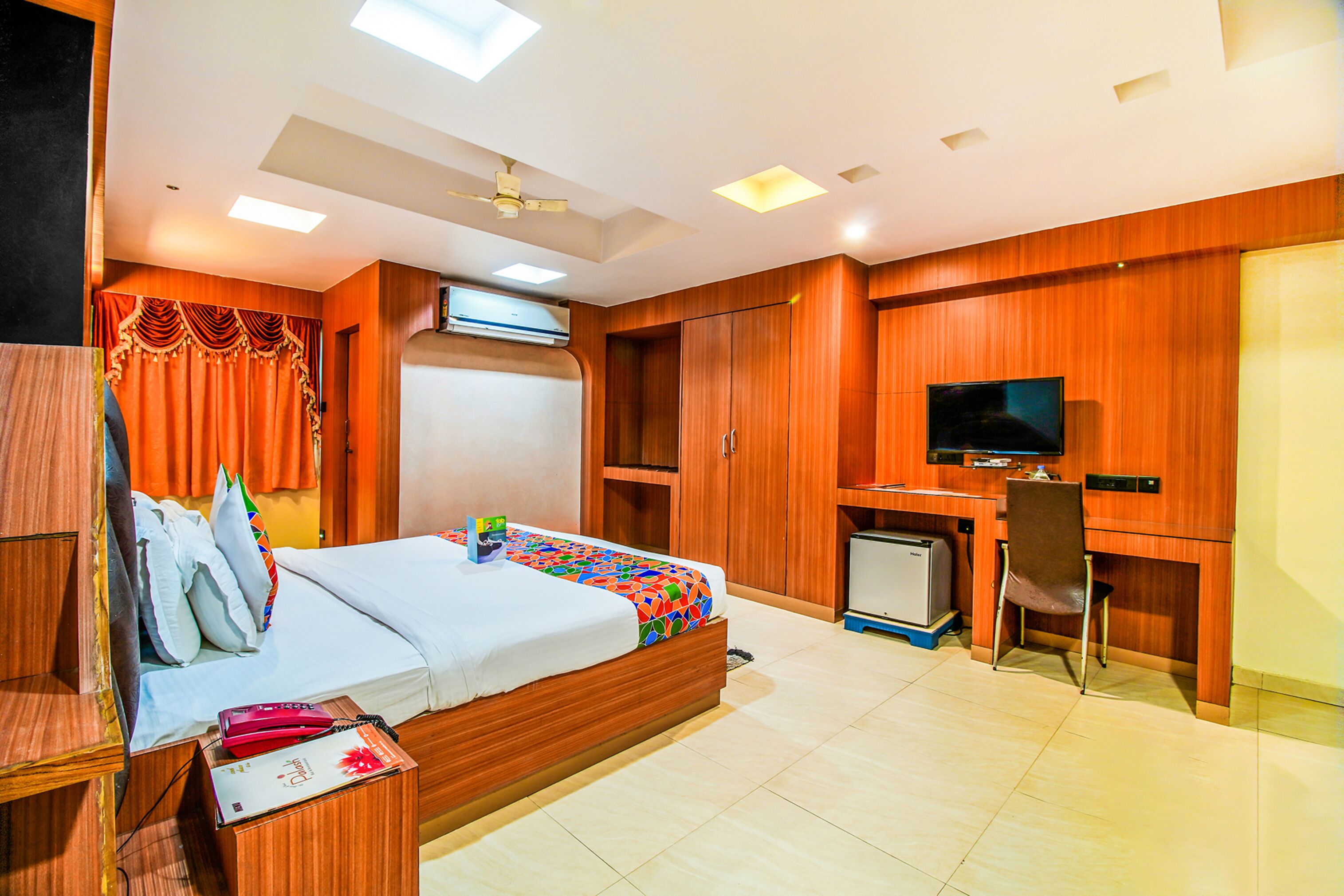 A hotel room with a bed, desk, chair, television, and a small refrigerator.