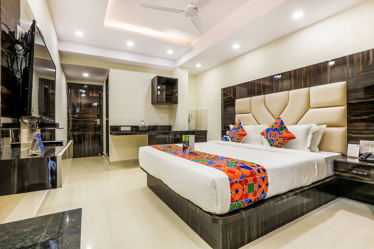 A modern hotel room with a large bed, a desk, and a television.
