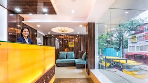 A hotel reception area with a reception desk, a chandelier, a sofa, and a view of the street outside. - FabHotel Crown Heights - Nr. Kormangala Club (Bengaluru)