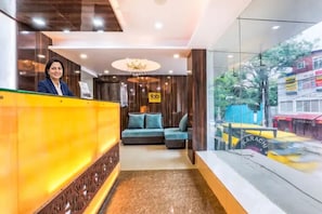 A hotel reception area with a reception desk, a chandelier, a sofa, and a view of the street outside. - FabHotel Crown Heights - Nr. Kormangala Club (Bengaluru)